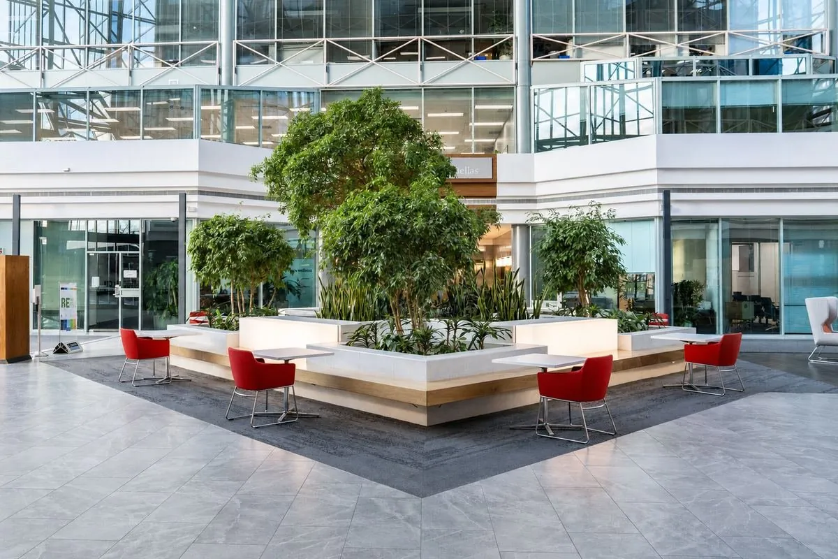 Commercial atrium lobby with a central planter and red chairs